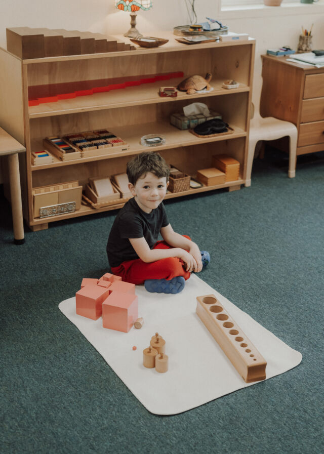 Building the pink tower on a work mat