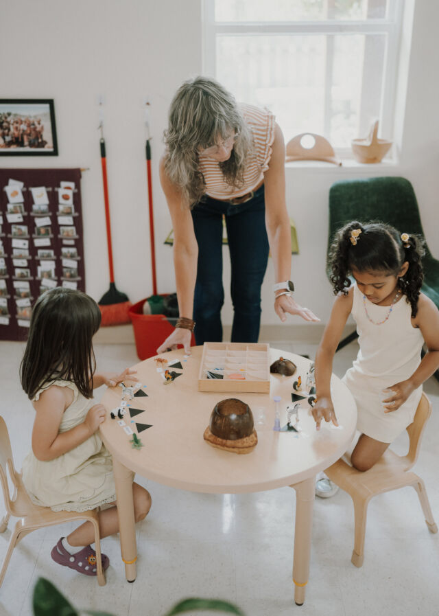 A guide presents animal figures to two children