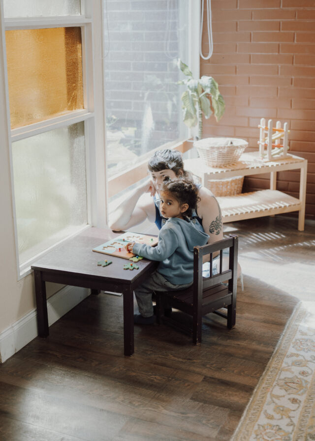 A guide and toddler work together at the window table