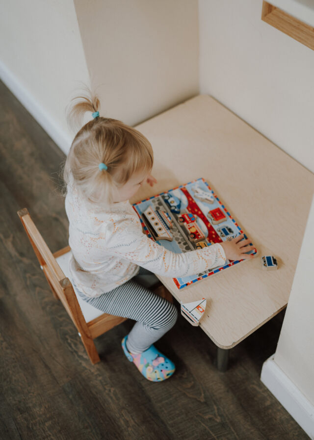 A toddler works a puzzle at the little table