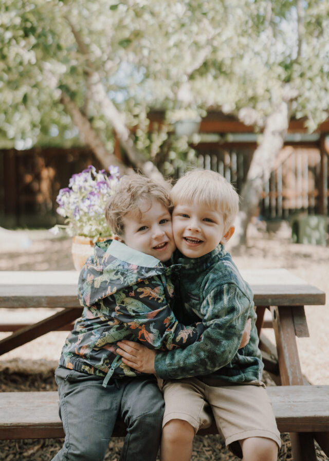 Two friends share a hug at the picnic table