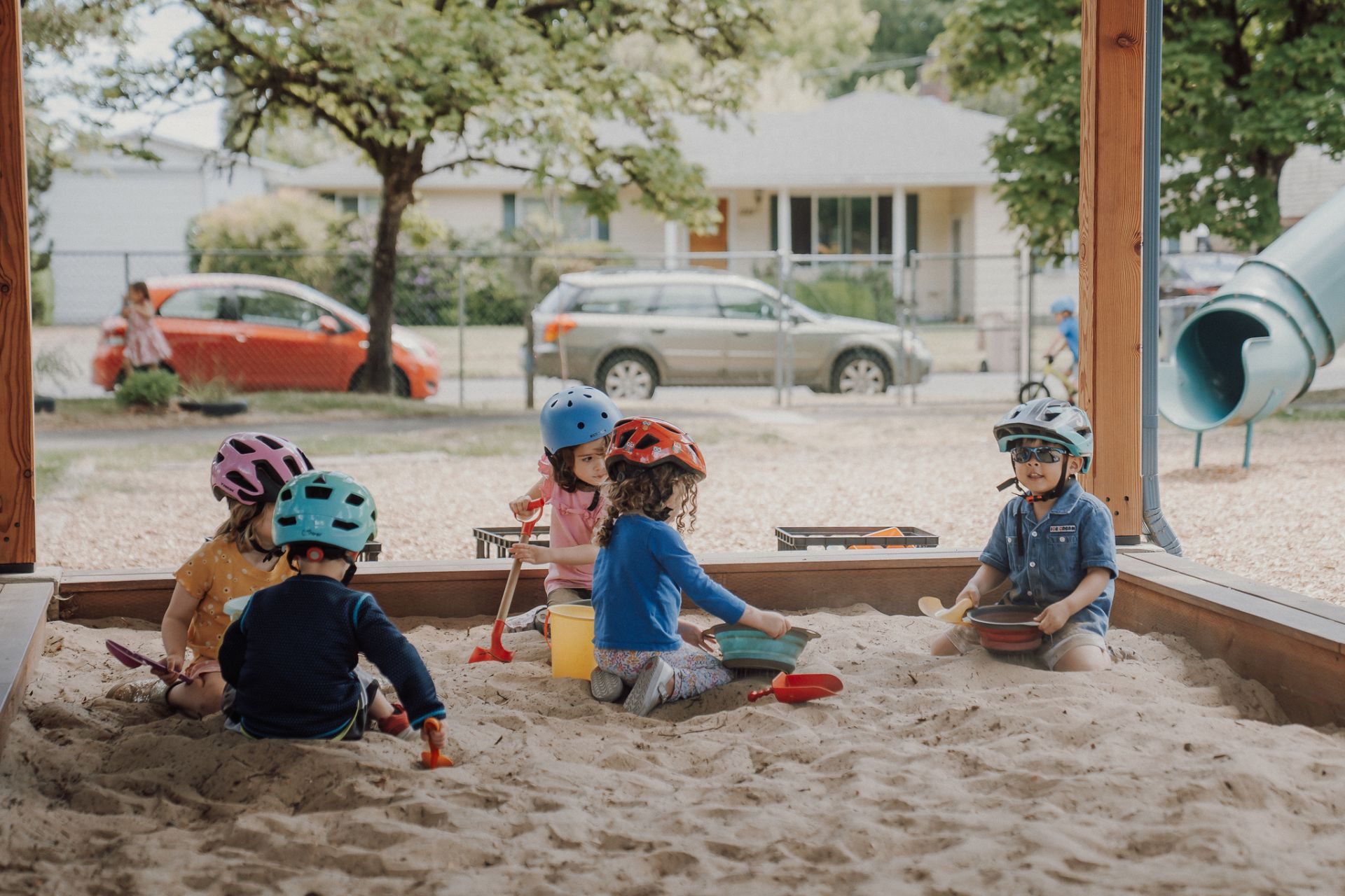 Children in helmets dig together in the sandbox