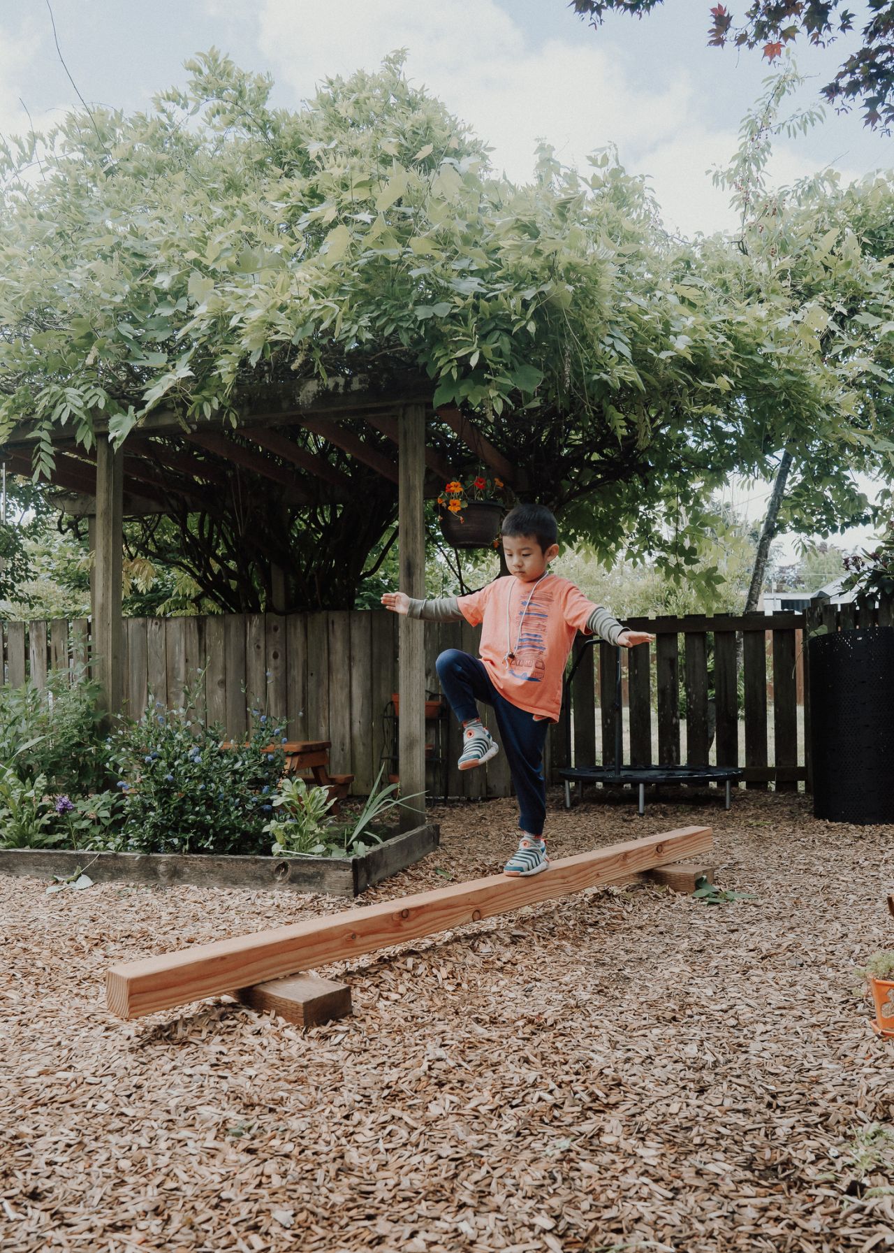 Balancing along the garden bed edge, arms out