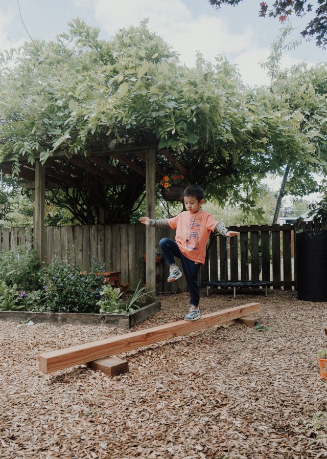 Balancing along the garden bed edge, arms out