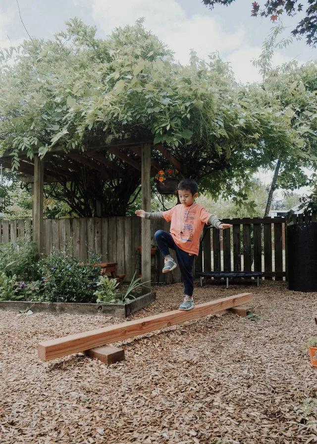 Balancing along the garden bed edge, arms out