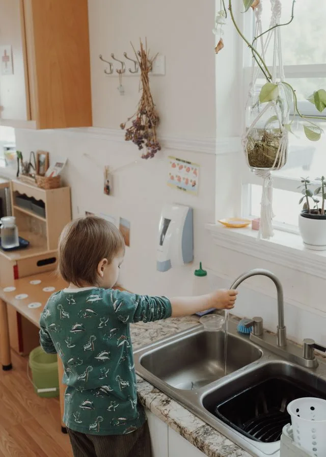 Toddler washing up at a child-height sink